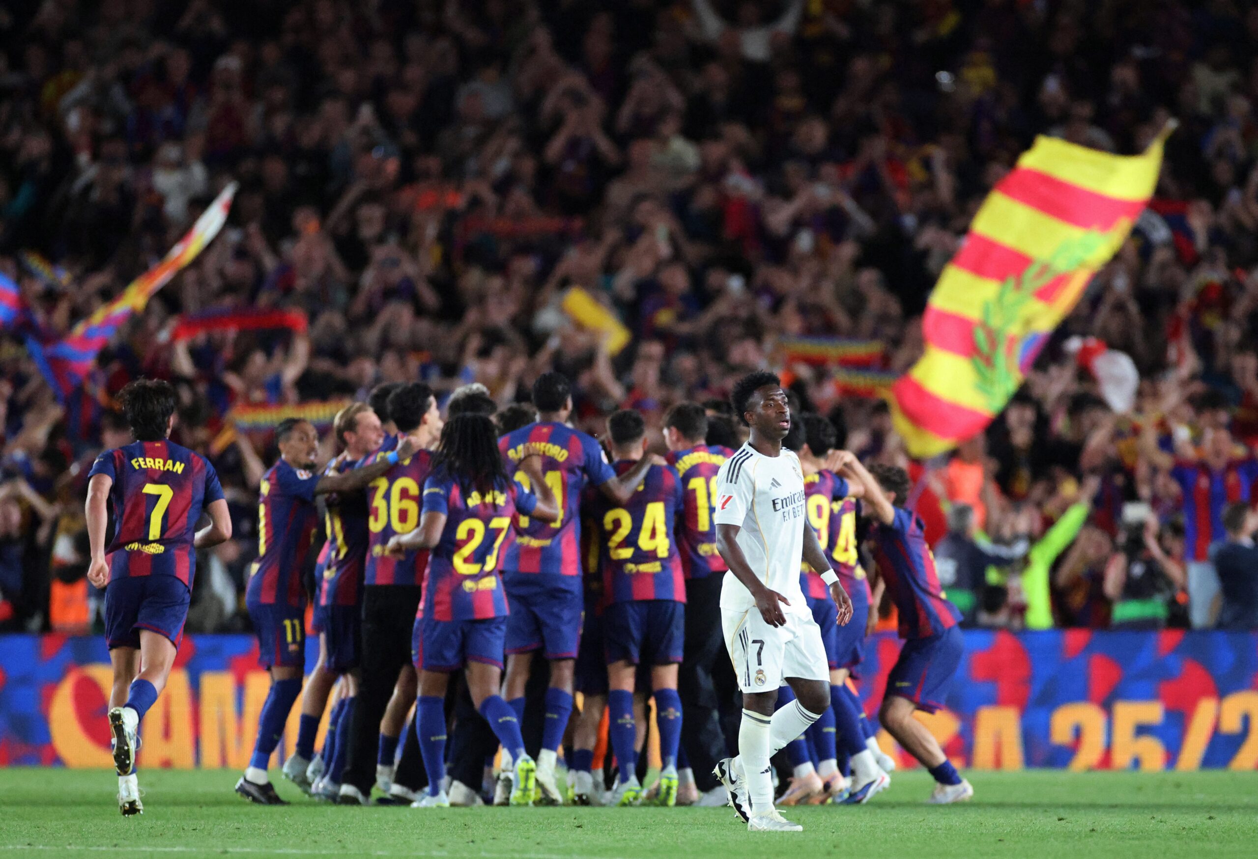 Real Madrid's Vinicius Junior looks dejected as the FC Barcelona players celebrate after winning the LaLiga